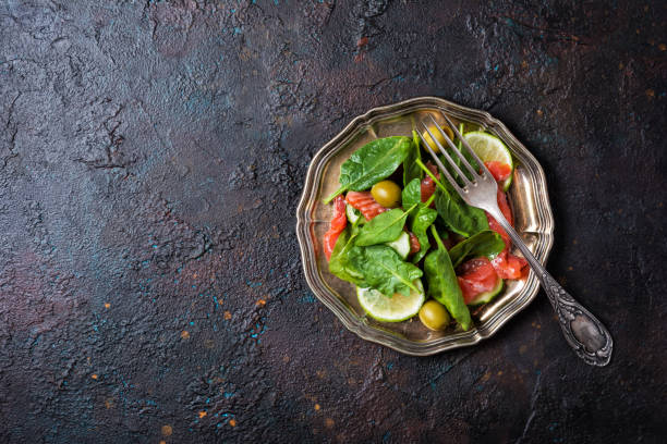 insalata fresca con pesce rosso, foglie di spinaci, olive verdi, lime e cetriolo - cucumbe foto e immagini stock