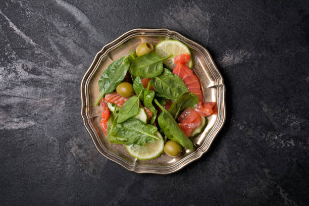 insalata fresca con pesce rosso, foglie di spinaci, olive verdi, lime e cetriolo - cucumbe foto e immagini stock