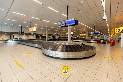 Hallway with baggage claim conveyor belts in Amsterdam Schiphol  airport almost deserted during the COVID-19 coronavirus outbreak
