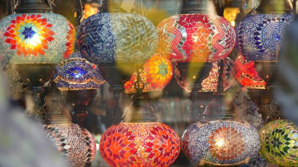 istock Colourful turkish lamps from glass mosaic glowing. Arabic multi colored authentic retro style lights. Many illuminated moroccan craft lanterns. Oriental islamic middle eastern decor. Shiny folk shop 1259944172