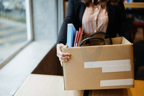 Asian woman holding cardboard box containing personal belongings looking for new job Asian woman holding cardboard box containing personal belongings after being fired by employer quitting a job stock pictures, royalty-free photos & images
