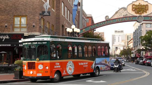 Gaslamp Quarter historic entrance arch sign. Orange retro trolley, Old Town Sightseeing Tour. San Diego, California USA - 30 JAN 2020: Gaslamp Quarter historic entrance arch sign on 5th avenue. Orange iconic retro trolley, hop-on hop-off bus and tourist landmark, Old Town Sightseeing Tour. trolley bus stock pictures, royalty-free photos & images