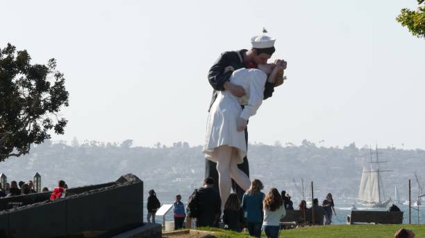 Unconditional Surrender Statue near USS Midway Museum. Symbol of V-J Day. San Diego, California USA - 23 FEB 2020: Unconditional Surrender Statue by Seward Johnson near USS Midway Museum. Symbol of Victory over Japan Day. Sailor kissing a woman, World War II memorial sculpture. People walking around and making photos. vj day stock pictures, royalty-free photos & images