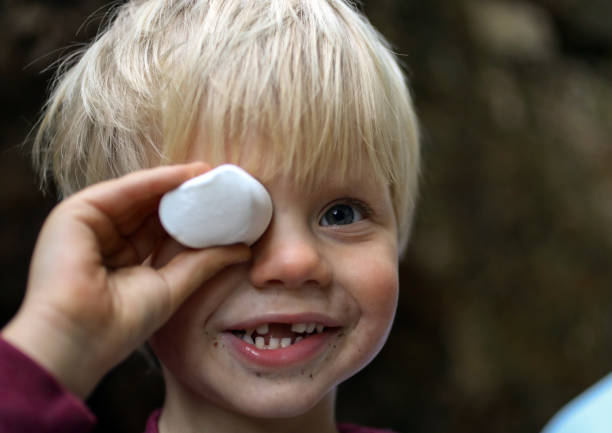 istock A young boy while on a hiking trip holds a marsmallow next to his eye. 1260020103