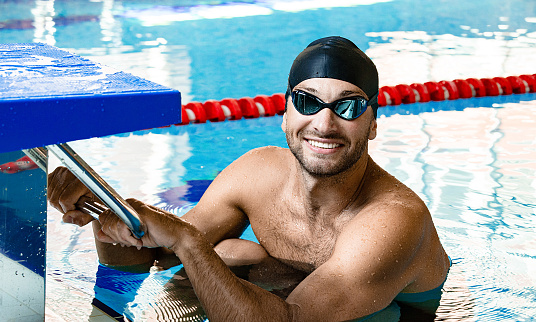 12-year-old multiracial boy practicing swimming at an indoor pool.