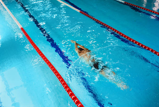 istock Swimmer dives underwater at blue swimming pool, top view. 1260022834