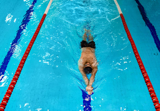 istock Swimmer floating in the swimming pool, top view. Relaxing bode on blue water pool 1260023336