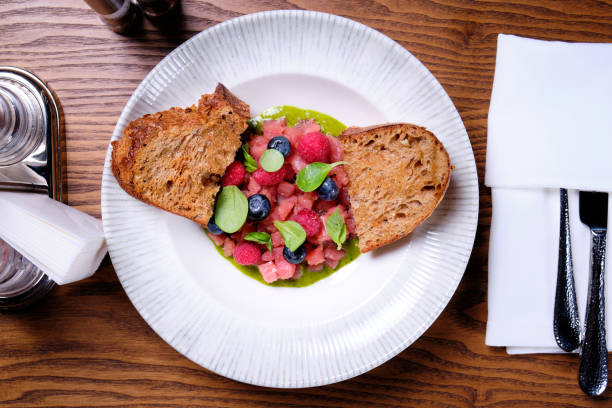 Tuna tartare with raspberries and blueberries in a white plate. Tuna tartare with raspberries and blueberries and bread in a white plate on a table in a restaurant. Relish stock pictures, royalty-free photos & images