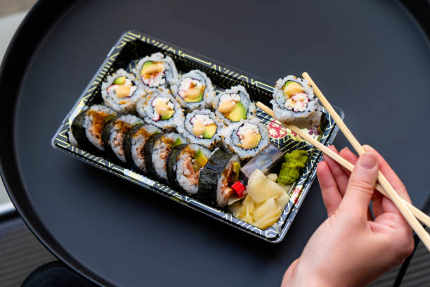 istock Young Woman Eating Sushi 1260044617