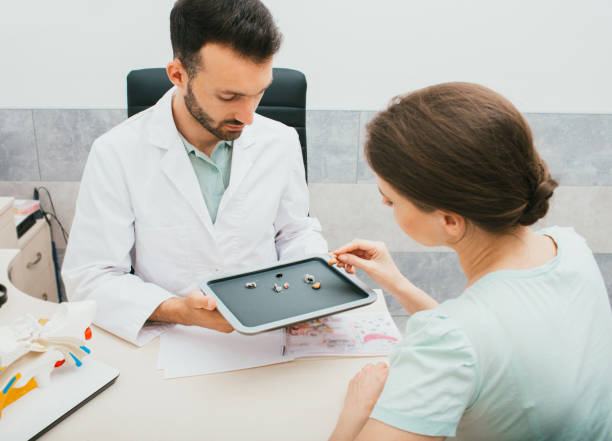 istock Hearing solution for adults. Audiologist selecting a hearing aid for a caucasian woman. Patient needs good hearing aids so that she can hear the sounds of the world. 1260061025