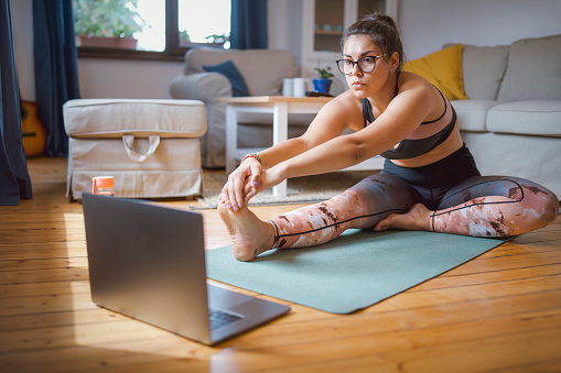 Young Latino woman stretching at home.