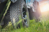Bottom view of large off-road car wheel on grass landscape