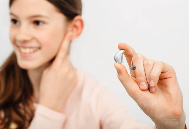 solução auditiva para crianças. garota segurando um aparelho auditivo, tratamento de surdez em crianças. audiologia - hearing aid isolated technology healthcare and medicine - fotografias e filmes do acervo