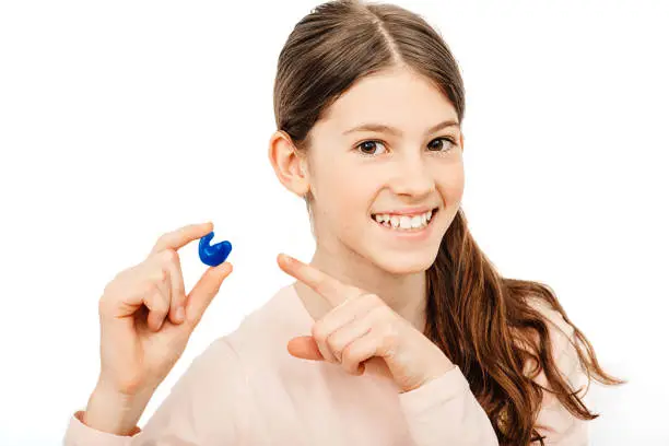 Photo of Advertising earplugs for children, a caucasian girl showing personally molded earplugs. Solution for noisy places