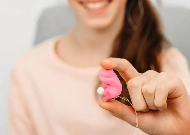 Photo of girl holding earplugs from an impression of an individual child ear. Earplug close-up. Personally molded earplugs. Part of the set