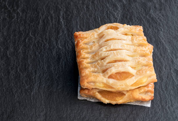 istock Puff pastry with apricot jam on black stone background 1260087191