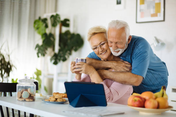istock Embraced senior couple using tablet during breakfast at home 1260091500