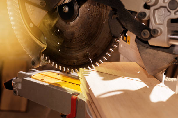 istock Carpenter working with power circular miter to cut wooden board against darkness. 1260105996