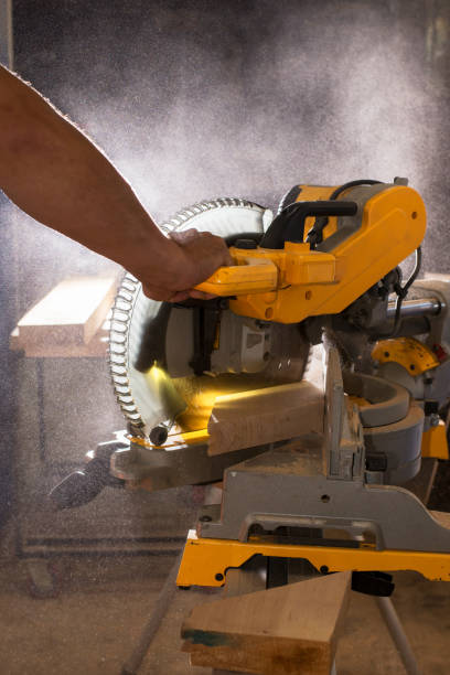 istock Carpenter working with power circular miter to cut wooden board against darkness. 1260107565