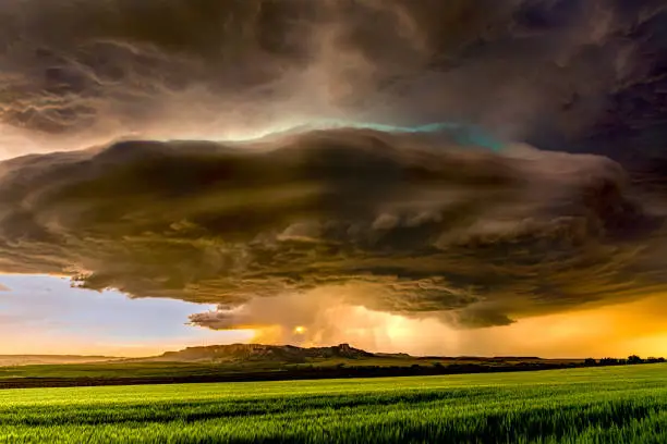 Panorama of a massive mesocyclone weather supercell, which is a pre-tornado stage, passes over a grassy part of the Great Plains while fiercely trying to form a tornado.