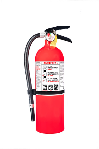 A classic red fire extinguisher isolated on white for use as a design element or safety inference for home and business protection.