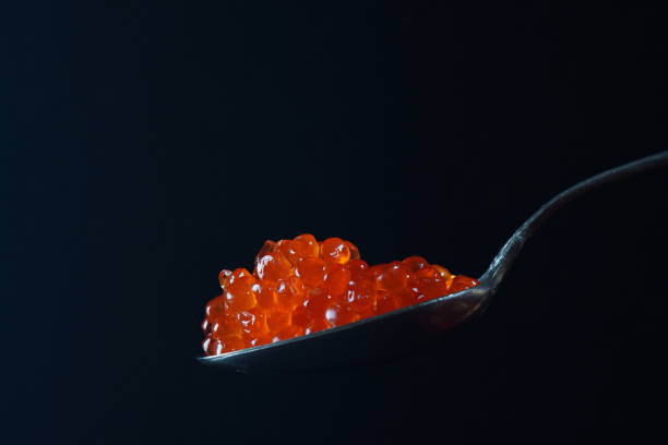 istock Red Caviar in a spoon over black background. 1260128824