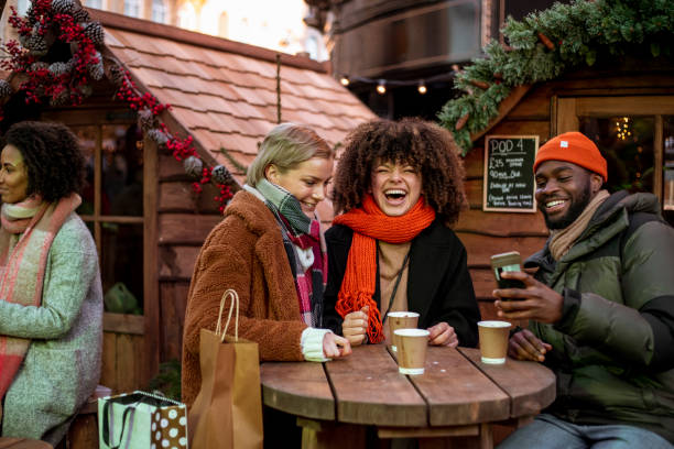 That's A Good Picture A front view of three friends sitting in a bar in the Xmas market looking through the pictures they have taken whilst walking around the market and visiting all the stalls. friends in bar with phones stock pictures, royalty-free photos & images