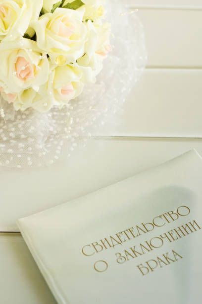 istock Bride's bouquet and marriage certificate on a light wood table. 1260136134