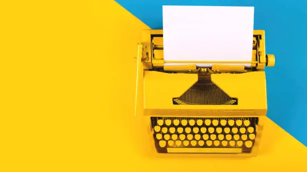 Photo of Yellow bright typewriter on a yellow background. Creativity concept