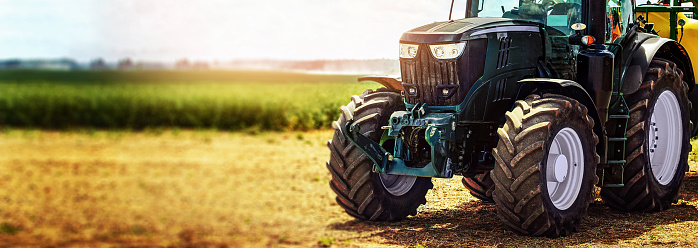 Aerial view of a tractor with crops spraying system works in the field.