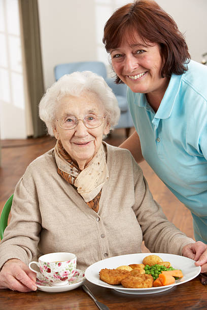 starszy kobieta serwowane posiłki przez opiekuna jest - eating female healthcare and medicine healthy lifestyle zdjęcia i obrazy z banku zdjęć