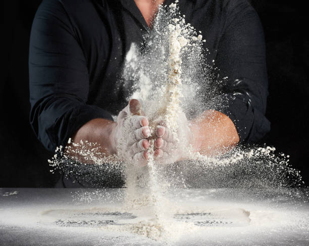 istock chef in black uniform sprinkles white wheat flour in different directions, product scatters dust 1260167004
