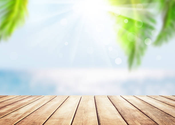 istock Wooden table top on blue sea and white sand beach background. 1260180951