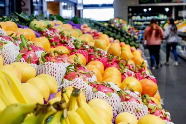 Fruit shop greengrocer display shelf with exotic fruits - mangoes, oranges, dragonfruits, bananas, avocadoes etc