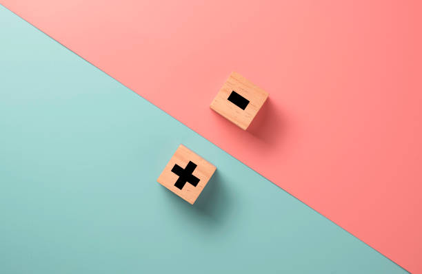 Black of plus and minus sign in opposite side of wooden cube on blue and pink background. Black of plus and minus sign in opposite side of wooden cube on blue and pink background. subtraction stock pictures, royalty-free photos & images