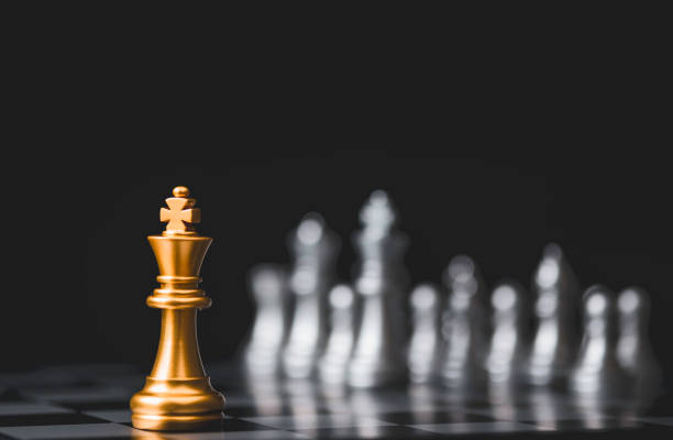 istock Golden king chess stand alone among  silver chess enemy at opposite side. Strategy decision for marketing business with competitors company concept. 1260191312