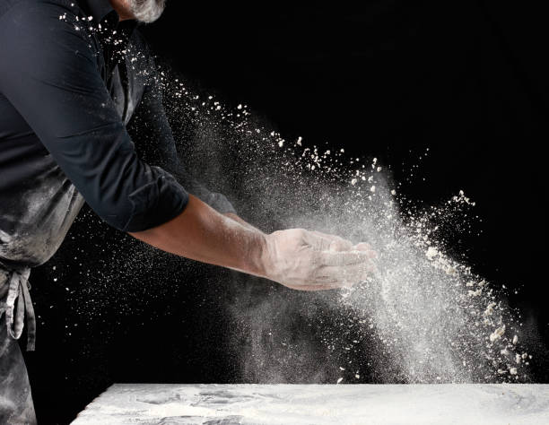 istock chef in black uniform sprinkles white wheat flour in different directions, product scatters dust 1260193496