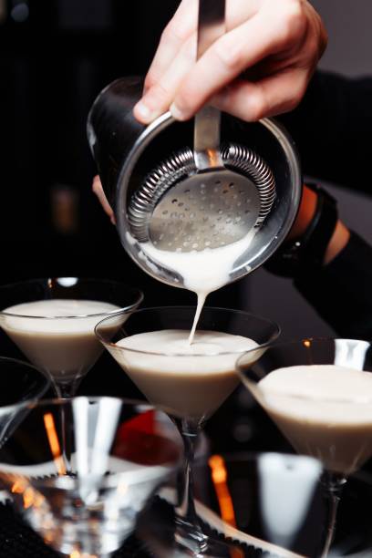 istock hands of a bartender holding a shaker pouring a drink into a martini glass 1260231849