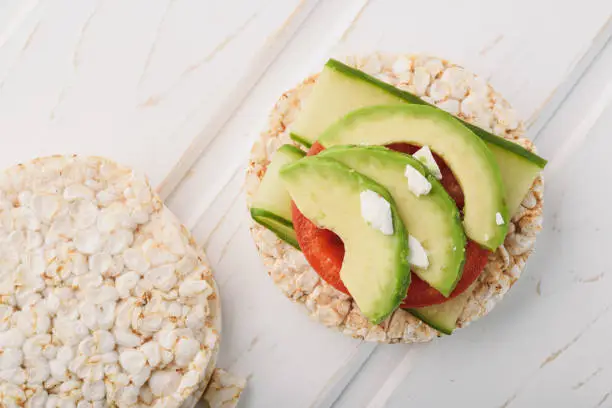 Top view vegan breakfast rice cake with avocado and tomato.