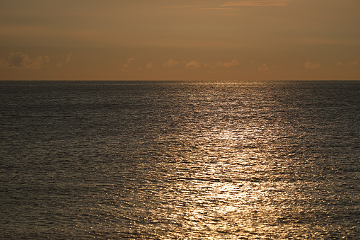 Sun path on light blue water with golden sunny bokeh circles on sea surface as motion background.