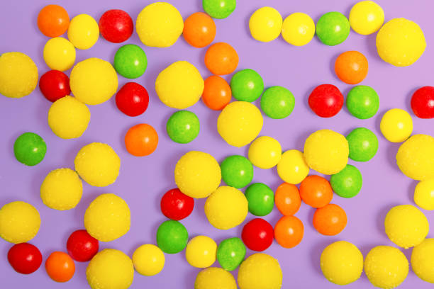 multicolored round candies on a violet background.