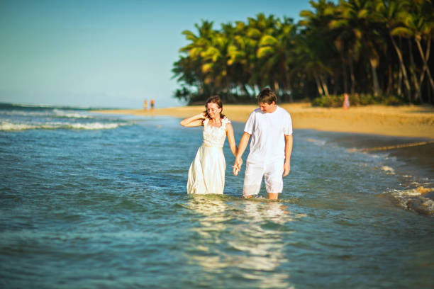 istock couple in white clothes in water on beach. 1260268049