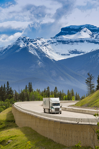 En route Revelstoke to Banff - June 2018: Large freight truck passing snow capped mountains on the Trans Canada Highway approaching Lake Louise, AB.