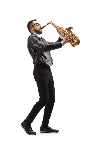 Full length profile shot of a musician playing a saxophone and wearing sunglasses  isolated on white background