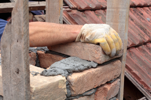 Mason hands making chimney with mortar and bricks