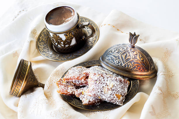 Turkish coffee with traditional turkish dessert cezerye and copper serving set. Festival of sacrifices. Feast of Ramadan. Cezerye is made with boiled carrots, sugar, pistachio and coconut. It is located dessert of Adana and Mersin cities in Turkey. café turco con cezerye de postre turco tradicional y set de porción de cobre. festival de sacrificios. fiesta del ramadán. cezerye se hace con zanahorias hervidas, azúcar, pistacho y coco. se encuentra postre de las ciudades de adana y mersin en turqu�