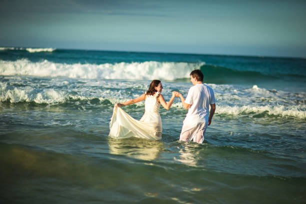 istock couple in white clothes in water on beach. 1260296760