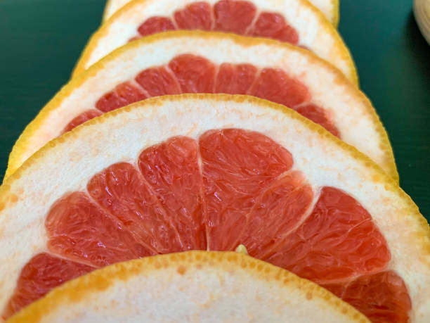 istock Sliced grapefruit in circles on a black table. Proper nutrition, vitamins, healthy snacks. 1260315154