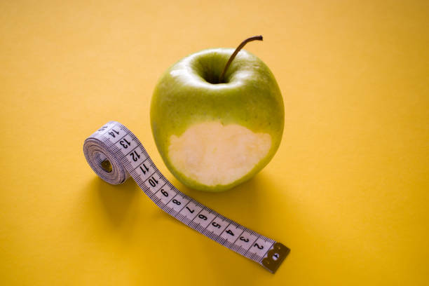 istock Bitten apple and measuring tape on yellow background 1260349972