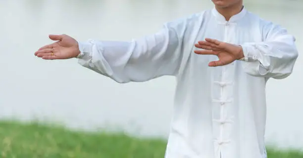 Photo of Asian man doing Tai Chi in the park.